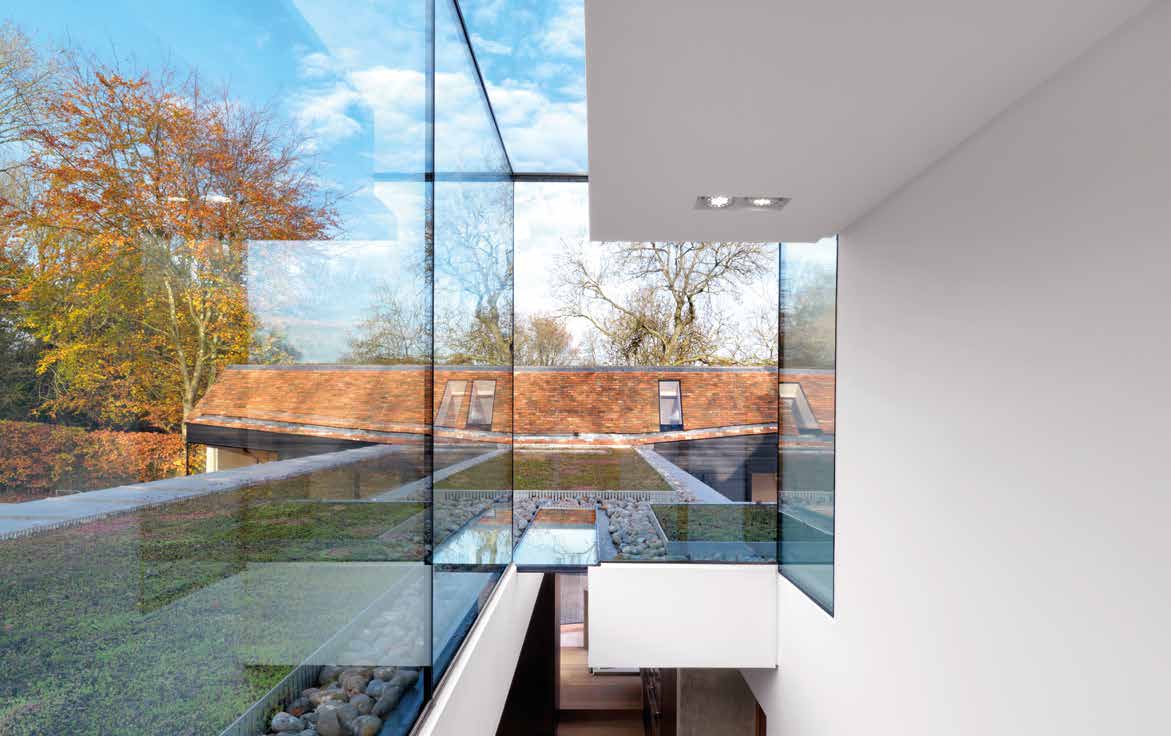 Fineline architectural glazing enclosing a bright double-height space with views of trees and surrounding rooftops